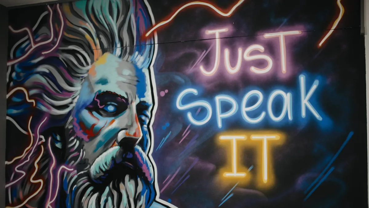 Неоновая надпись Just Speak It на граффити-стене филиала