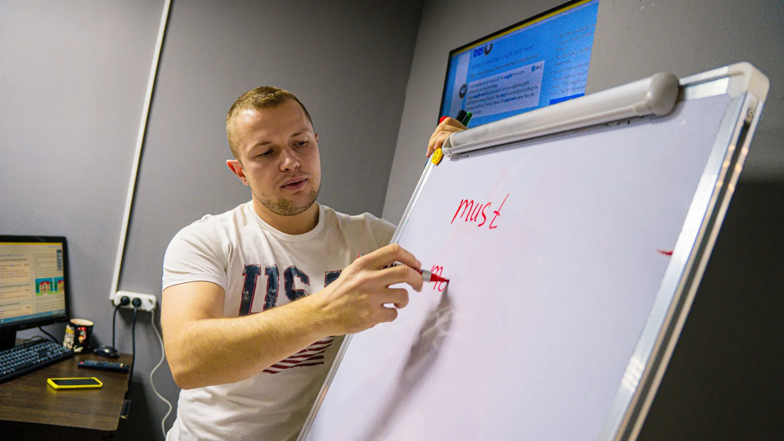 Преподаватель объясняет грамматику у доски на занятии английским